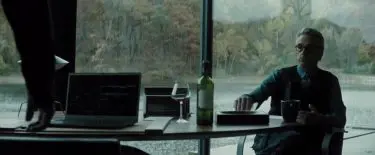 Alfred seated at Bruce Wayne's desk where we see a Baccarat wine glass