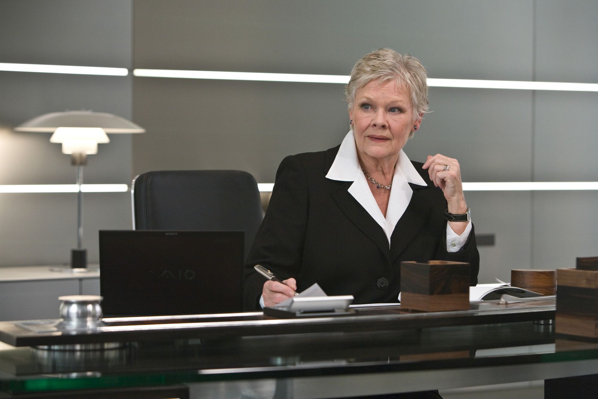 Judi Dench as M in Quantum of Solace sitting in an Interstuhl Silver Chair lights and lamps and desk in film